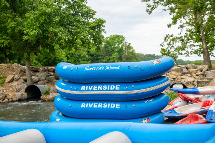 Stacked blue rafts labeled 'Riverside' near a river with trees.