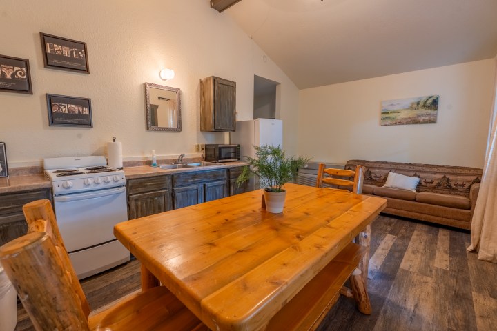 Cozy kitchen with dining table, wooden cabinets, and sofa in open-plan space.