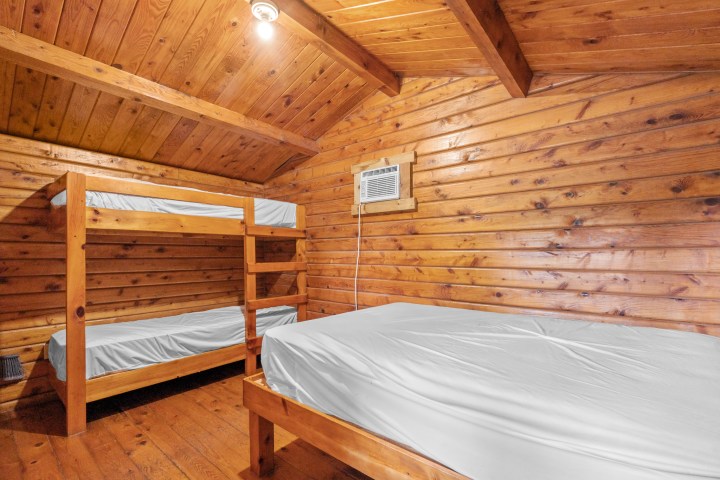 Wood-paneled room with bunk beds and a single bed.